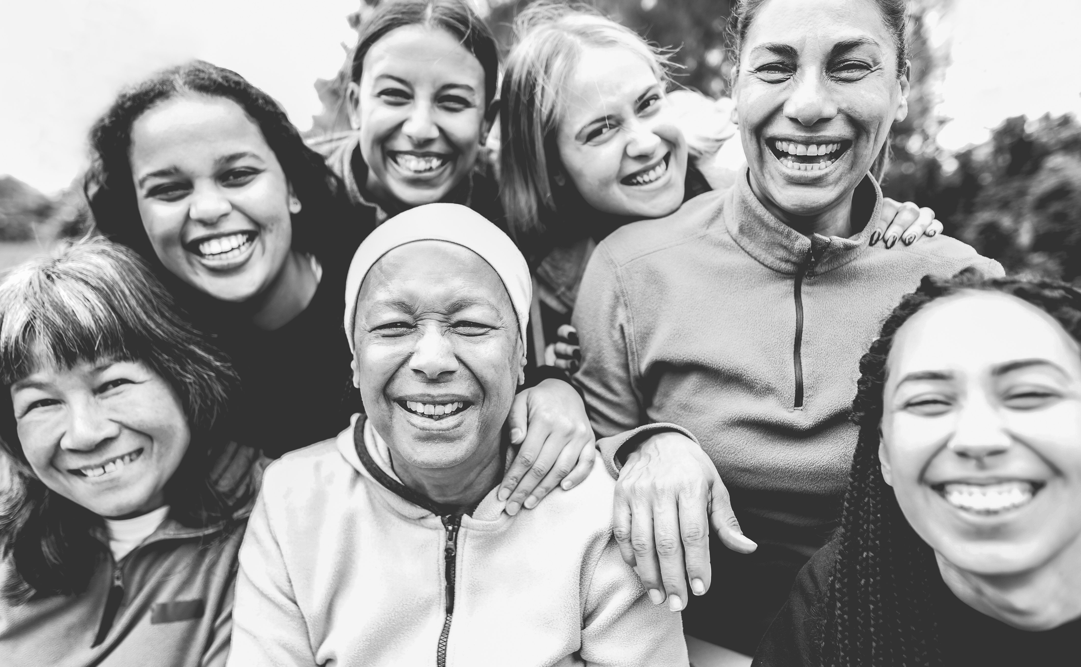 Multiracial women friends laughing on camera after yoga class workout outdoor - Sport and women day concept - Main focus on center african female face - Black and white editing